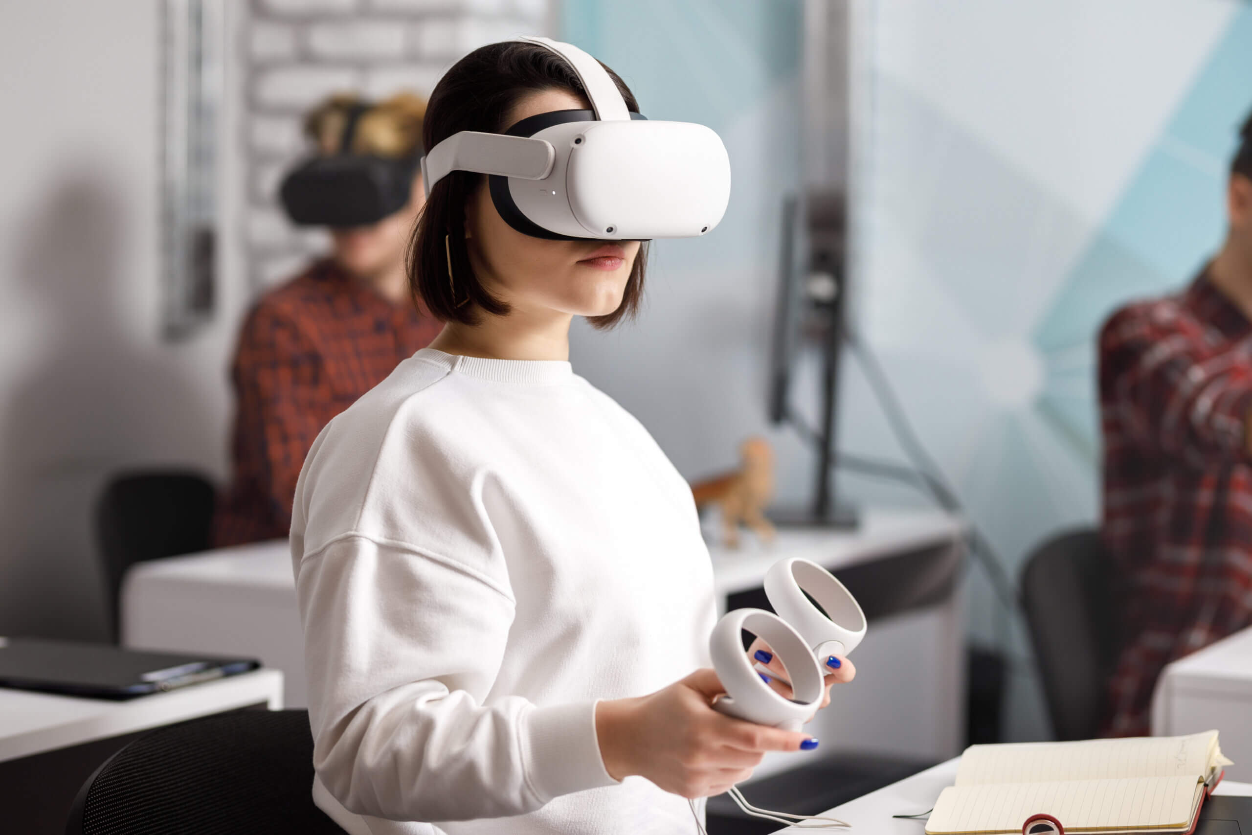 team of four creative engineers working with virtual reality, young woman testing VR glasses or goggles sitting in the office room